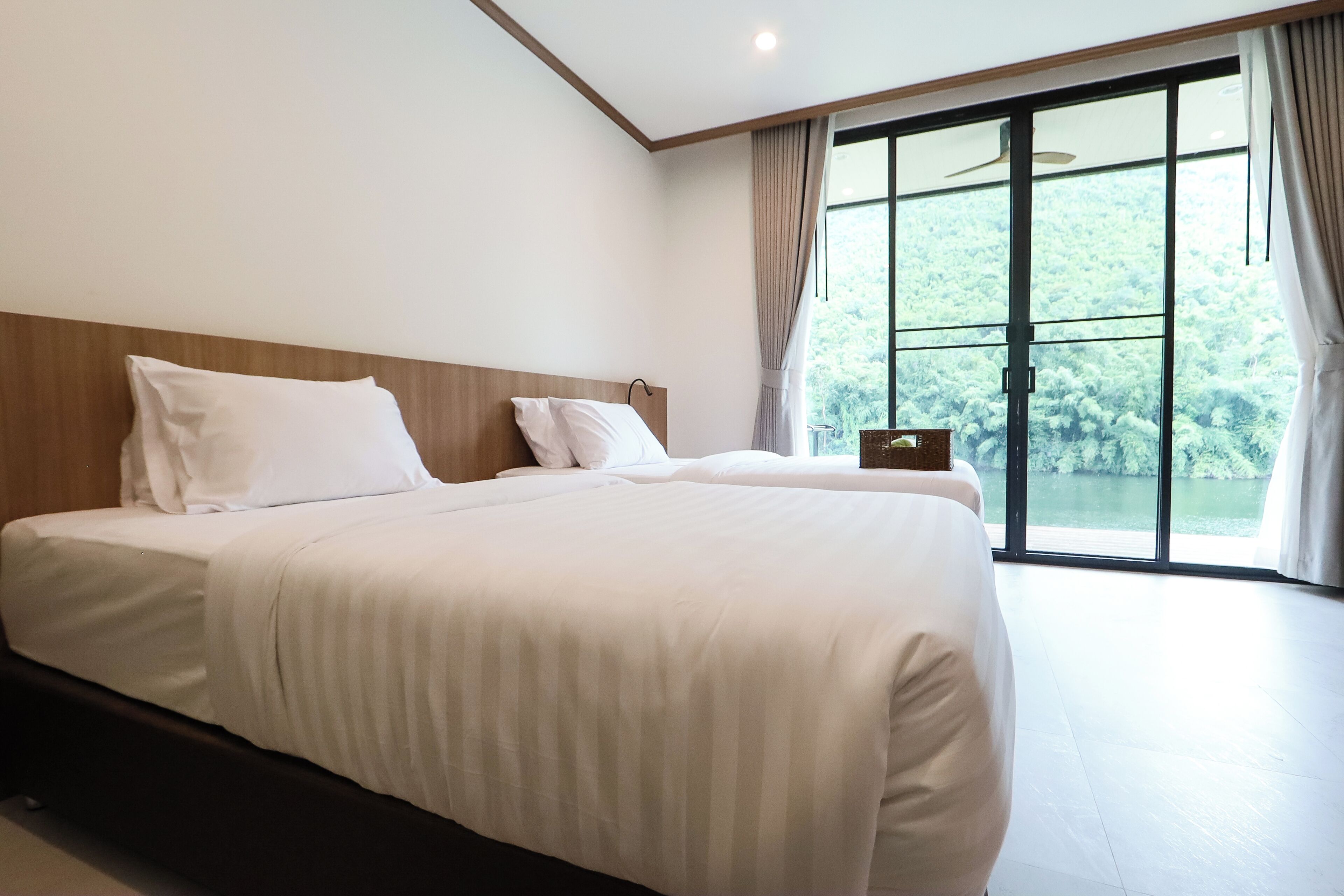 Een moderne slaapkamer met een groot bed, een houten hoofdbord en uitzicht op een meer door grote ramen.
