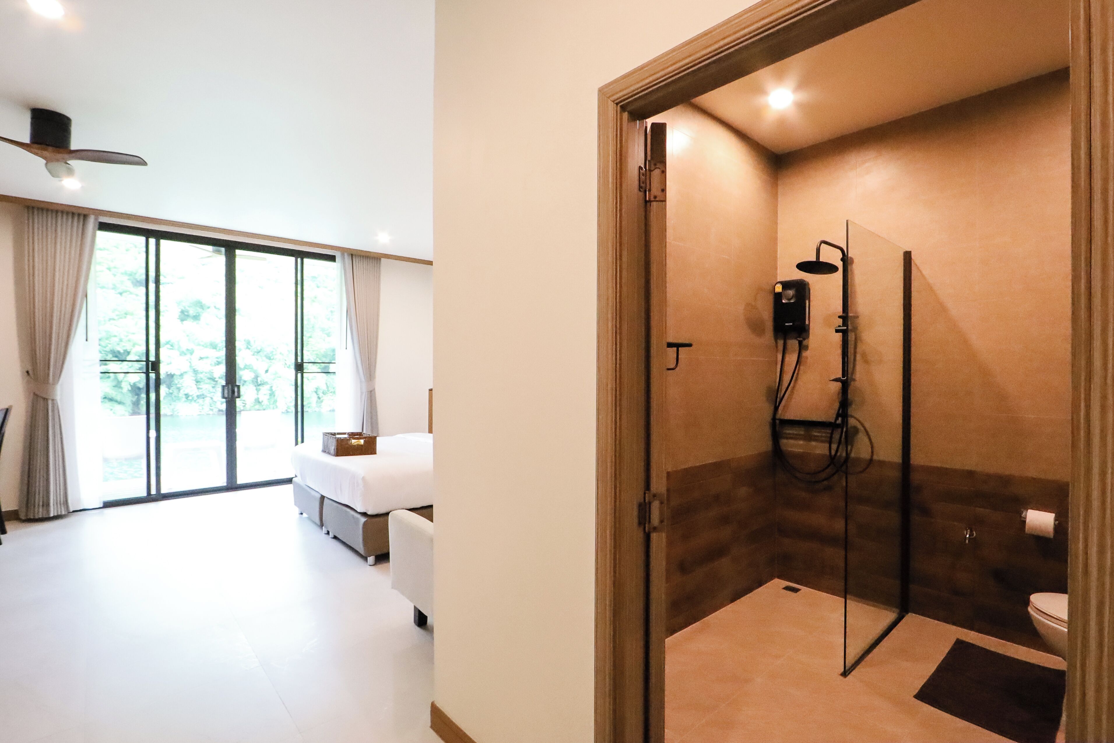 Une salle de bain moderne avec une douche à parois de verre, des toilettes et une grande fenêtre avec des rideaux.