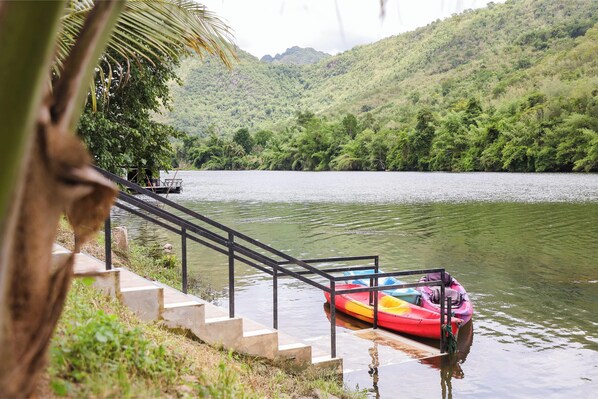 A boat docked at a concrete staircase leading to a water body, surrounded by lush greenery and hills.