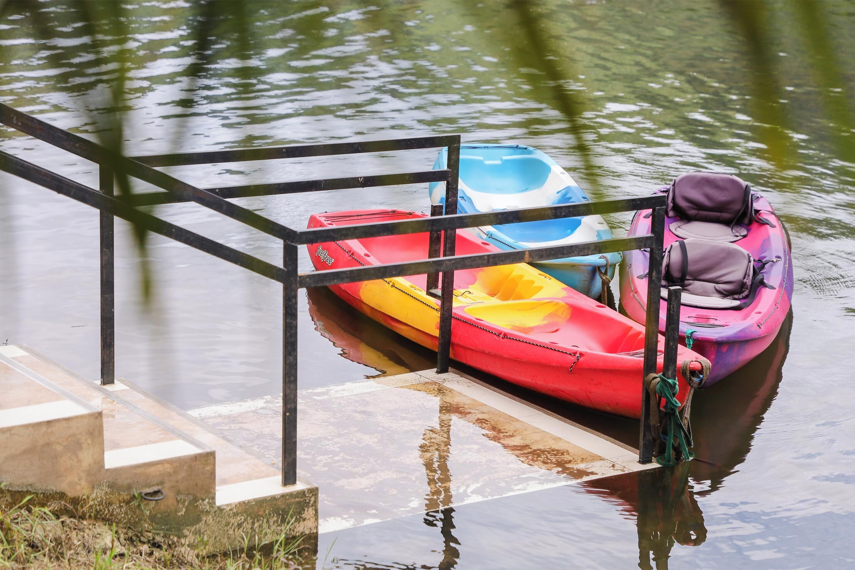 A dock with a metal railing and a row of colorful kayaks tied to it.