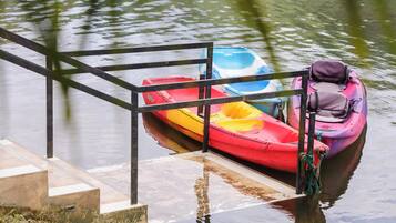A dock with a metal railing and a row of colorful kayaks tied to it.