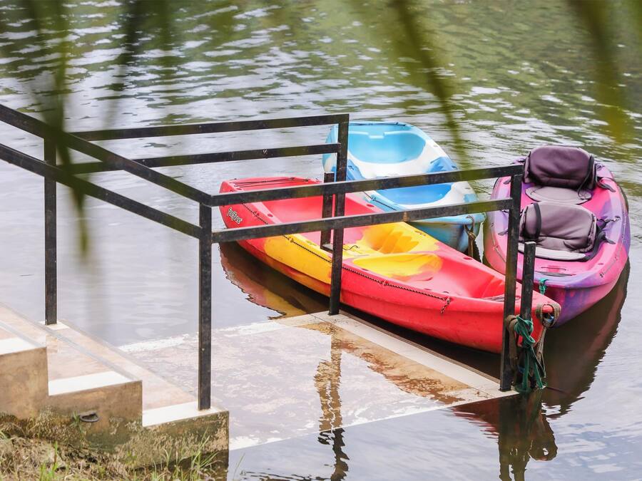 A dock with a metal railing and a row of colorful kayaks tied to it.