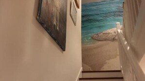 Un escalier menant à un point de vue sur la plage, avec un tableau accroché au mur.