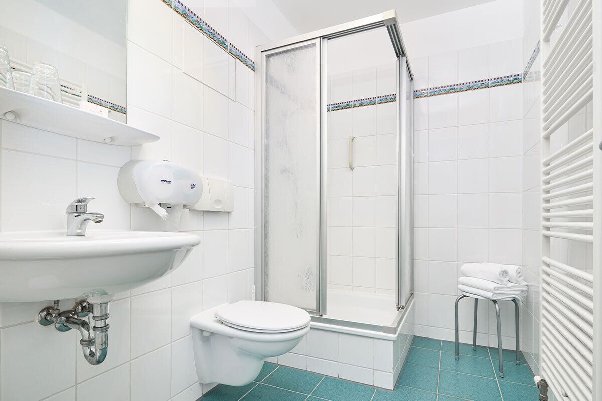 A modern bathroom with a white sink, toilet, and shower.