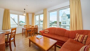 A furnished living room with a sofa, coffee table, and dining set. - Appartementhaus Haus Strandperle (Zinnowitz)
