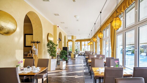 A spacious hotel lobby with high ceilings, large windows, and a central plant. - Appartementhaus Haus Strandperle (Zinnowitz)