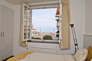 Een slaapkamer met een groot raam, een bed, een radiator en een lamp.