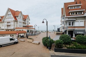 Een gebouw aan de kust met een rood pannendak, een witte gevel en een balkon.