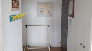 A room with a white metal drying rack, a framed artwork on the wall, and a door with a mirror and a key lock. - Apartement de 1 à 4personnes 200m de la mer (La Turballe)