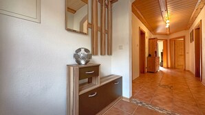 A hallway with wooden flooring, a decorative metal sphere, and a wooden cabinet with drawers. - Ferienwohnung im Bayerischen Wald mit Terrasse (Viechtach)