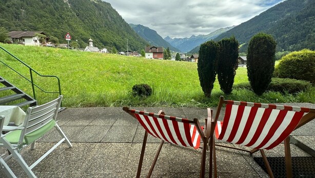 A terrace with a view of a mountainous landscape, a chair, and a small table. - Cosy Apartment in Gortipohl With Garden (Sankt Gallenkirch)