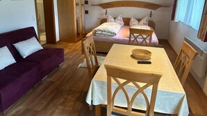 A cozy room with a bed, a purple sofa, a wooden table, and a wardrobe. - Cosy Apartment in Gortipohl With Garden (Sankt Gallenkirch)