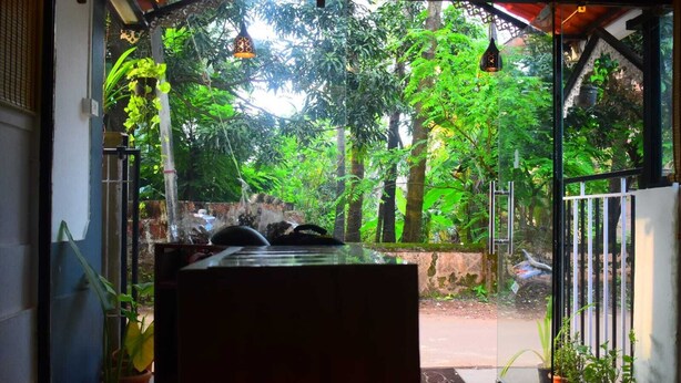 A room with a view of a lush garden through a glass door. - ROSHNI - THE LUXURY GUEST HOUSE (Baga)