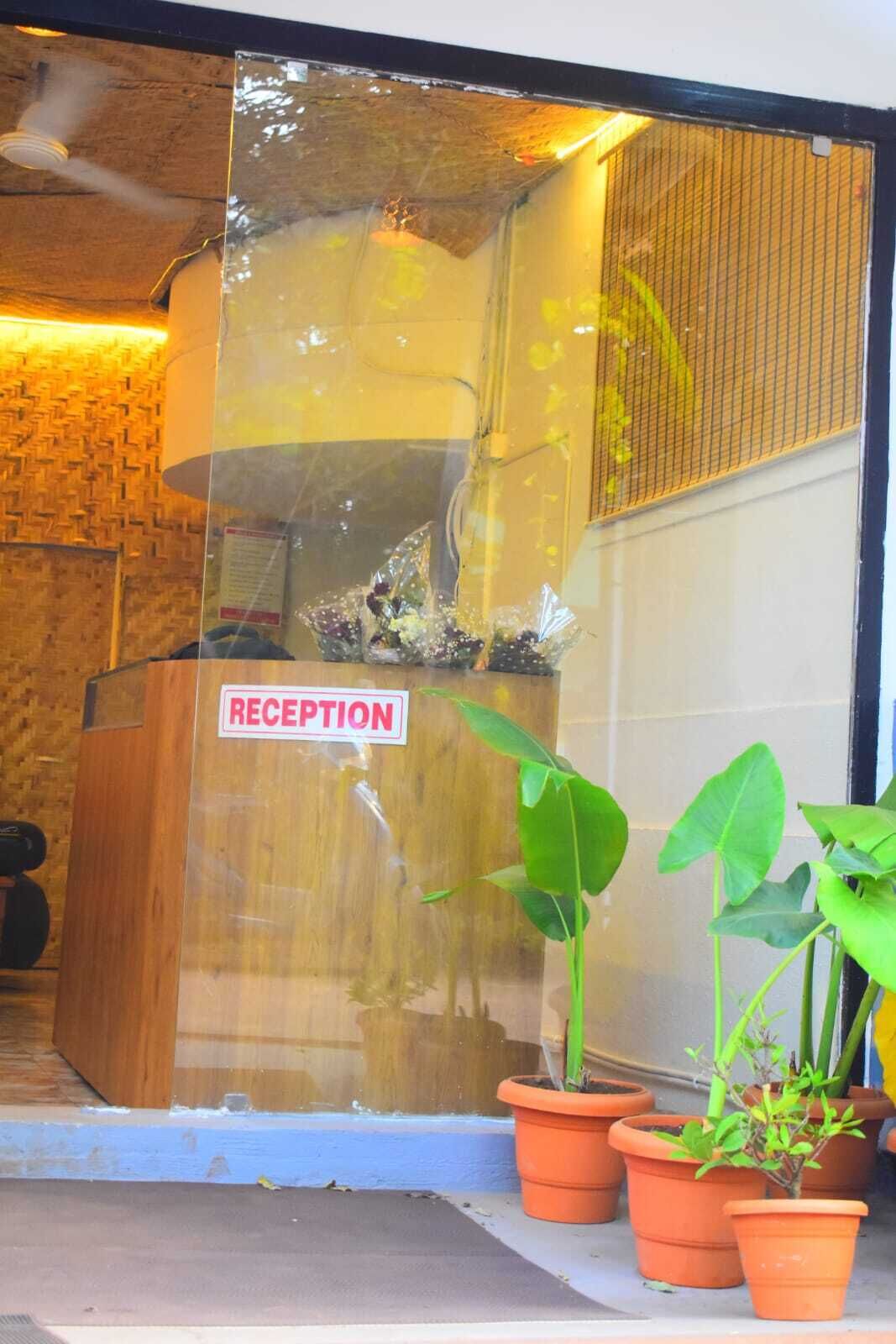 A reception area with a 'RECEPTION' sign, a wooden reception desk, and potted plants outside.