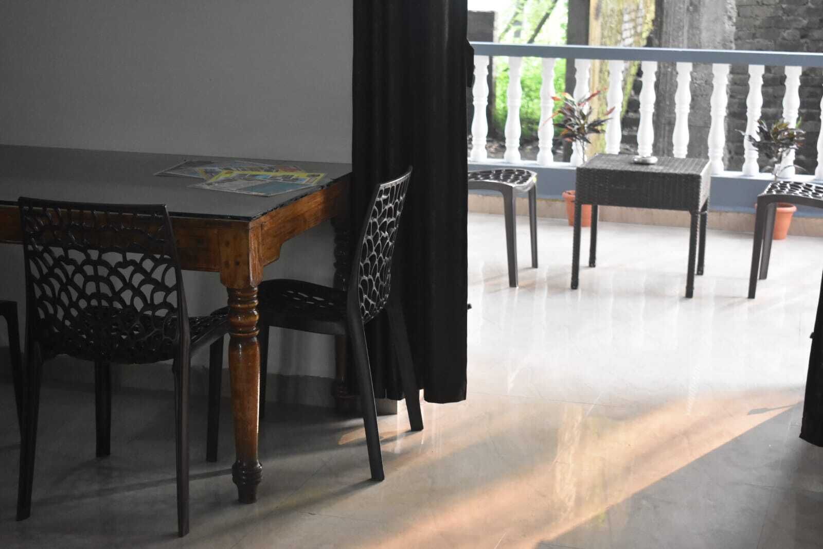Comedor con mesa y sillas de madera, un balcón con plantas en macetas y vista a la vegetación.