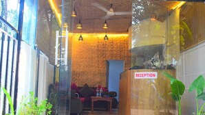 A reception area with a wooden reception desk, a ceiling fan, and hanging pendant lights. - ROSHNI - THE LUXURY GUEST HOUSE (Baga)
