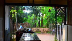A glass door leading to a lush garden with potted plants and hanging lights. - ROSHNI - THE LUXURY GUEST HOUSE (Baga)