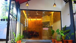 A reception area with a glass door, potted plants, and hanging pendant lights. - ROSHNI - THE LUXURY GUEST HOUSE (Baga)