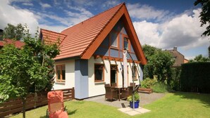 A two-story house with a red roof, a balcony, and a garden. - Luerssen Lindenhopsweg (Wunstorf)