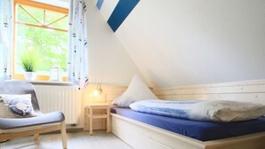 A cozy bedroom with a sloped ceiling, a wooden bed, a chair, and a small table. - Luerssen Lindenhopsweg (Wunstorf)