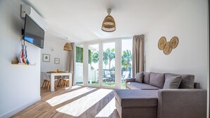 A modern living room with a grey sofa, a dining area with a table and chairs, and a large sliding glass door leading to a balcony with outdoor furniture. - Sunstay Portview Marina Flat II Benalmadena (Benalmádena)