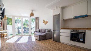 A modern kitchen with a refrigerator, oven, and wooden flooring. - Sunstay Portview Marina Flat II Benalmadena (Benalmádena)
