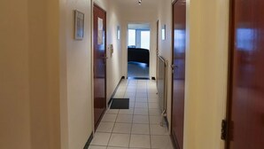 A hallway with a tiled floor, wooden doors, and a ceiling light. - Beachfront Stay in Middelkerke for 6 (Middelkerke)