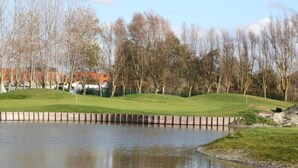 A calm lake with a grassy area and trees in the background. - Beachfront Stay in Middelkerke for 6 (Middelkerke)