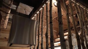 A rustic wooden cabin interior with exposed beams and a large metal appliance, possibly a refrigerator, mounted on the wall. - Holiday Home in Sprimont With Forest (Sprimont)