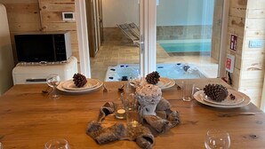 A wooden dining table set with plates, wine glasses, and decorative items like pinecones and a ceramic vase. - Holiday Home in Sprimont With Forest (Sprimont)