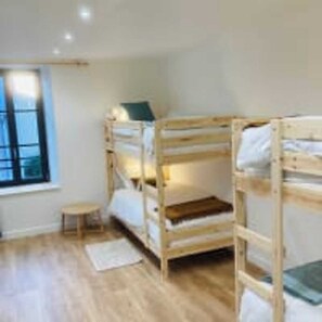 A room with three bunk beds, a small table, and a window. - Le Domaine des Figuiers - Le Gîte des Pèlerins (Servon)