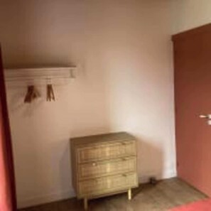 A room with a wooden dresser, a door, and a wall-mounted shelf. - Le Domaine des Figuiers - Le Gîte des Pèlerins (Servon)