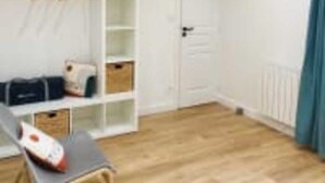 A room with a wooden floor, a white door, a white shelving unit, and a blue curtain. - Le Domaine des Figuiers - Le Gîte des Pèlerins (Servon)
