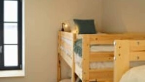 A bunk bed room with a window, a small stool, and a wooden dresser. - Le Domaine des Figuiers - Le Gîte des Pèlerins (Servon)