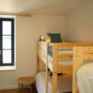 A bunk bed room with a window, a small stool, and a wooden dresser. - Le Domaine des Figuiers - Le Gîte des Pèlerins (Servon)