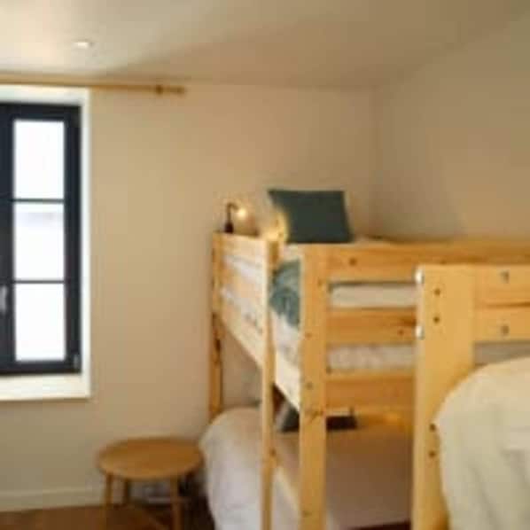 A bunk bed room with a window, a small stool, and a wooden dresser. - Le Domaine des Figuiers - Le Gîte des Pèlerins (Servon)