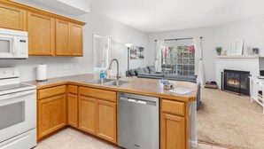 A modern kitchen with wooden cabinets, a dishwasher, and a built-in oven. - Beacon at the Lakes - Cozy & Bright 2bd/2ba Ground Level Condo (Windsor)