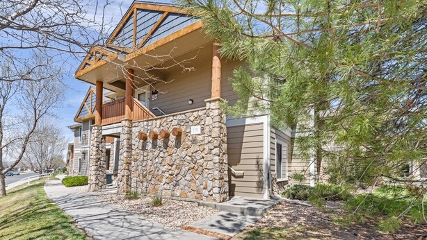 A two-story house with a stone facade, a balcony, and a clear view of the surrounding neighborhood. - Beacon at the Lakes - Cozy & Bright 2bd/2ba Ground Level Condo (Windsor)