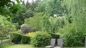 Un jardin avec deux chaises longues et une haie.