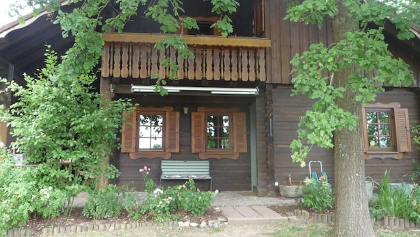 Une cabane en bois rustique dotée d’un balcon, d’un banc à l’extérieur et d’un espace jardin.