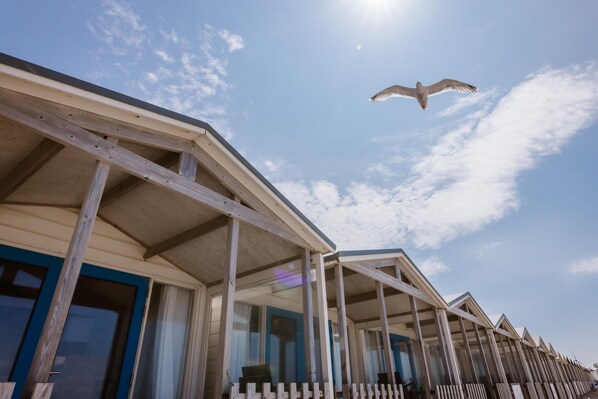 A row of beach houses with a wooden deck and a clear sky.