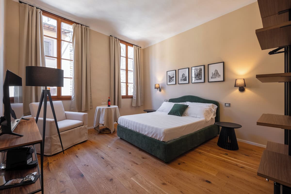 A bedroom with a bed, a desk, a chair, a lamp, and a window with curtains.