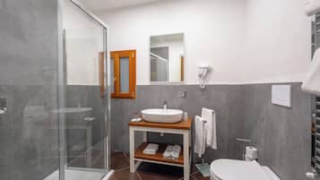 Une salle de bain moderne avec une douche à parois de verre, un lavabo blanc, un meuble-lavabo en bois et des toilettes.