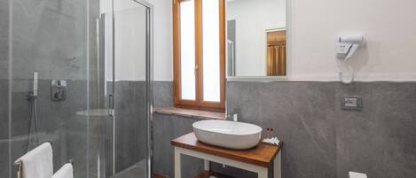 A modern bathroom with a glass shower enclosure, a wooden vanity with a white sink, and a toilet.