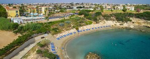 Vista aérea de una zona costera con playa, puerto deportivo y edificios residenciales.