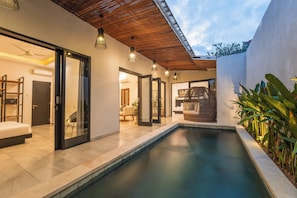 Ein modernes Haus mit Schwimmbad, Holzboden und Glastüren, die in einen Wohnbereich führen.