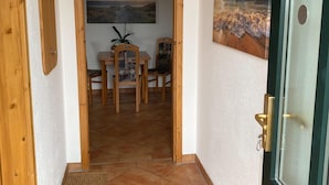 A hallway with a wooden door, a dining area with a table and chairs, and two paintings on the walls. - Hideaway, Pruchten- Baltic Coast (Pruchten)