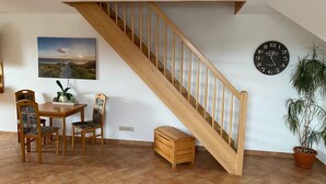 A dining area with a wooden staircase, a clock, and a potted plant. - Hideaway, Pruchten- Baltic Coast (Pruchten)