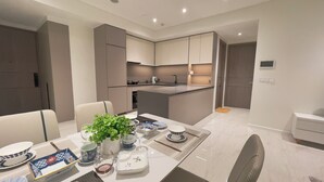 A modern kitchen with integrated dining area, featuring a central island, built-in cabinets, and a seating arrangement. - The Opera Residence Bitexco view (Ho Chi Minh City)