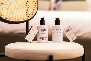 Une chaise sur laquelle sont posées trois bouteilles de produits de soins pour les cheveux et le corps, ainsi que deux cartes de visite.